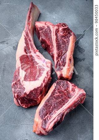 Black Angus Prime raw beef dry aged steak, tomahawk, t bone or porterhouse and club steak, on gray stone background 98450033