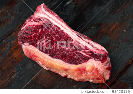 Raw fresh meat dry aged Club Steak, on old dark  wooden table background, with copy space for text 98450129
