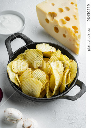 Salty potato chips snack  with Cheese and Onion , with dipping sauces tomato dip sour cream, on white stone  surface 98450239
