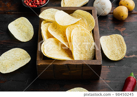 Salty potato chips snack , on old dark wooden table Salty potato chips snack , on old dark wooden table 98450245