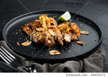 Delicious roasted shrimps with garlic, curry and mango sauce, on plate, on black background Delicious roasted shrimps with garlic, curry and mango sauce, on plate, on black background 98450272