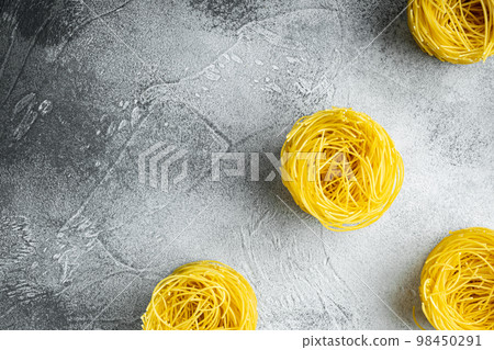 Unooked Italian Tagliolini paglia pasta, on gray stone background, top view flat lay, with copy space for text Unooked Italian Tagliolini paglia pasta, on gray stone background, top view flat lay, with copy space for text 98450291