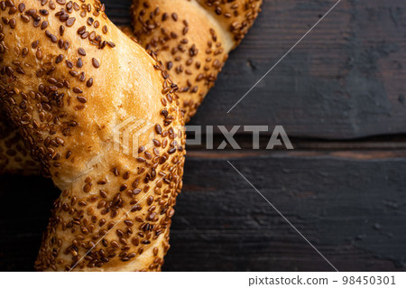Fresh baked simit sesame bagel , on old dark  wooden table background, top view flat lay, with copy space for text 98450301