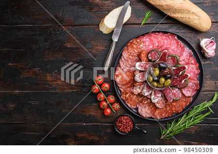 Antipasto platter cold meat with chorizo, fuet,salami, salchichon and longaniza on dark wooden background with space for text 98450309