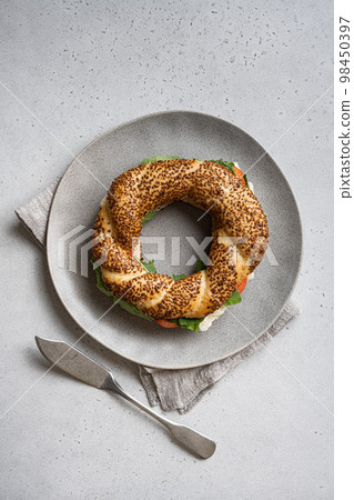 Bagel simit, breakfast, with lettuce, tomato olive and cheese, on gray concrete table background, top view flat lay, with copy space for text Bagel simit, breakfast, with lettuce, tomato olive and cheese, on gray concrete table background, top view flat lay, with copy space for text 98450397
