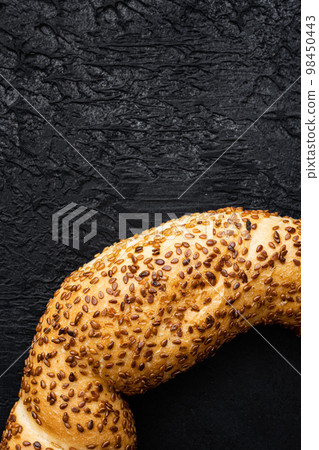 Fresh baked simit sesame bagel, on black dark stone table background, top view flat lay, with copy space for text Fresh baked simit sesame bagel, on black dark stone table background, top view flat lay, with copy space for text 98450443