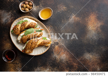 Traditional Turkish bagel simit, breakfast, on old dark rustic table background, top view flat lay, with copy space for text Traditional Turkish bagel simit, breakfast, on old dark rustic table background, top view flat lay, with copy space for text 98450471