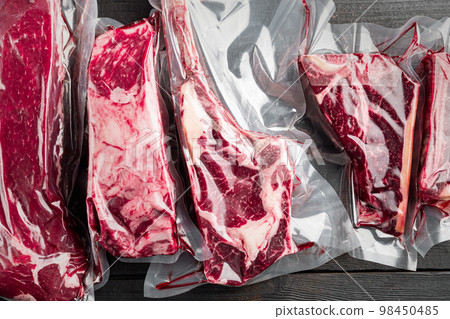 Beef steak vacuum, tomahawk, t bone, club steak, rib eye and tenderloin cuts, on black wooden table background, top view flat lay 98450485