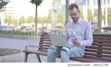 Young Adult Man making Successful Online Payment on Laptop Young Adult Man making Successful Online Payment on Laptop 98451799