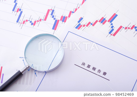 Earnings report, stock chart and magnifying glass 98452469