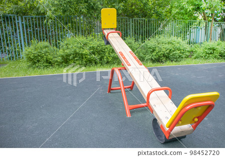 Balancing swing in the form of a wooden board on an empty outdoor playground, children's play area 98452720