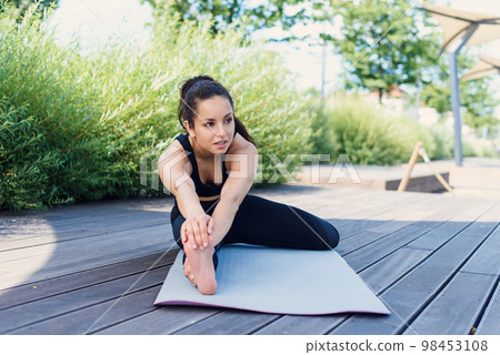 Sporty young woman makes yoga exercising with yoga mat at the park outdoor. Active lifestyle concept. Sporty young woman makes yoga exercising with yoga mat at the park outdoor. Active lifestyle concept. 98453108