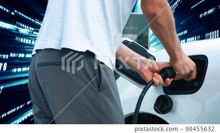 Progressive man charge electric car with technology background of binary code. Progressive man charge electric car with technology background of binary code. 98455632