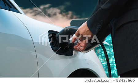 Progressive businessman recharge electric car with charging point in the city. 98455660