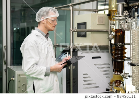Apothecary scientist recording data from CBD oil extractor in laboratory. Apothecary scientist recording data from CBD oil extractor in laboratory. 98456111