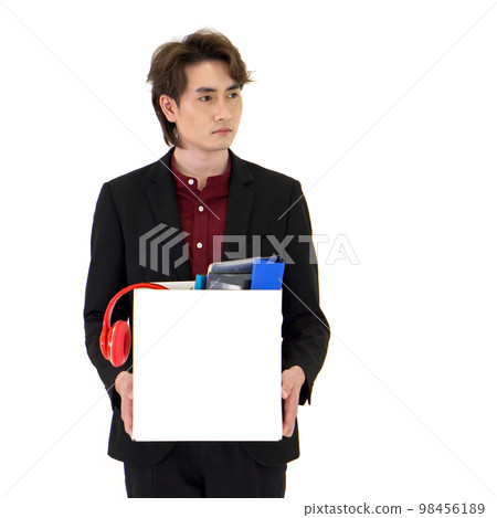 Young Asian businessman in black suit showing absent-minded, stressed and unhappy expression, holding paper box of belongings collected from office in the get fired day. Young Asian businessman in black suit showing absent-minded, stressed and unhappy expression, holding paper box of belongings collected from office in the get fired day. 98456189