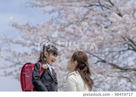 A daughter and her mother conversing on the promenade with cherry blossoms 98459717
