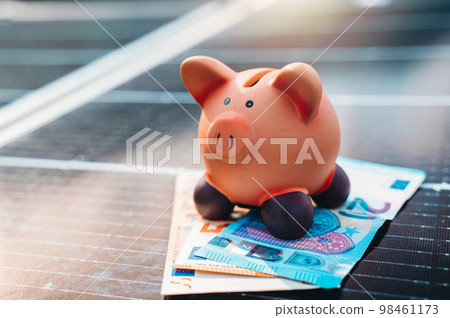 Piggybank on solar panel concept of money saved by using clean energy 98461173