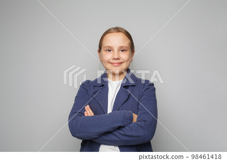 Little smiling cute pretty clever kid child girl 10 year old wearing blue school uniform standing  98461418