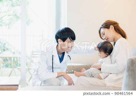 A baby being examined by a doctor who visited the house 98461564