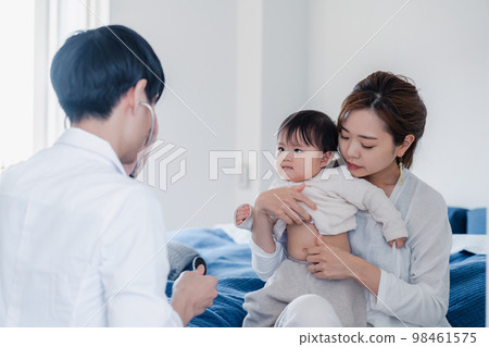 A baby being examined by a doctor who visited the house 98461575