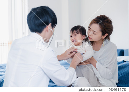 A baby being examined by a doctor who visited the house 98461578
