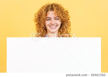 Smiley woman with curly hair holding a blank panel 98462360