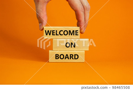 Welcome on board symbol. Wooden blocks with words 'Welcome on board'. Beautiful orange background, businessman hand. Business, welcome on board concept, copy space. Welcome on board symbol. Wooden blocks with words 'Welcome on board'. Beautiful orange background, businessman hand. Business, welcome on board concept, copy space. 98465508