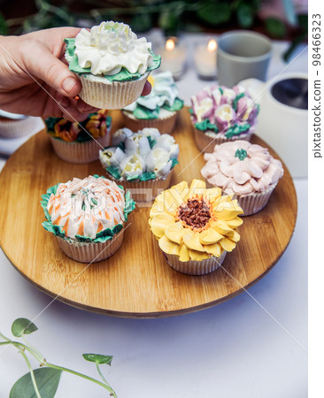 Woman holding a tasty fresh cupcake decorated with flower icing on beautiful wedding party table, high tea,Mothers day Holiday Woman holding a tasty fresh cupcake decorated with flower icing on beautiful wedding party table, high tea,Mothers day Holiday 98466323