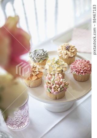 Fresh cupcakes with whipped cream and devorative flower icing served on a plate on party table, wedding,baby shower,high tea, Birthday holiday 98467183