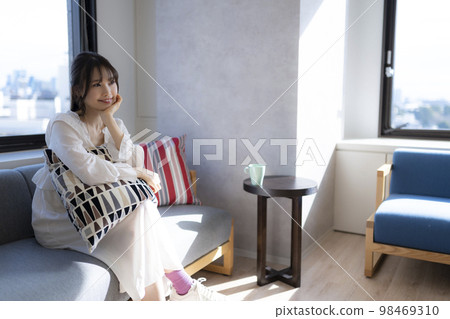 女人在辦公室的沙發上放鬆,喝杯咖啡 女人在辦公室的沙發上放鬆,喝杯咖啡 98469310