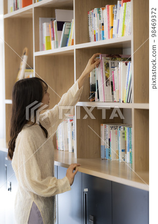 在辦公室書架上找書的年輕女人 98469372