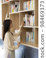 在辦公室書架上找書的年輕女人 98469373