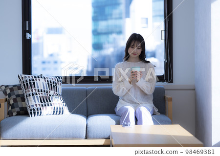 女人在辦公室的沙發上放鬆，喝杯咖啡 98469381