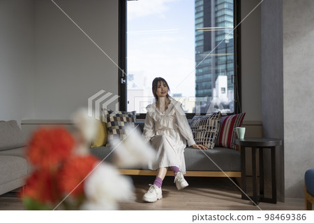 Woman relaxing on the sofa in the office. There is a coffee cup. 98469386