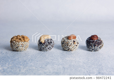 Variety of homemade energy balls with nuts on light background. Organic candies made of dried fruits and nuts.  98472241