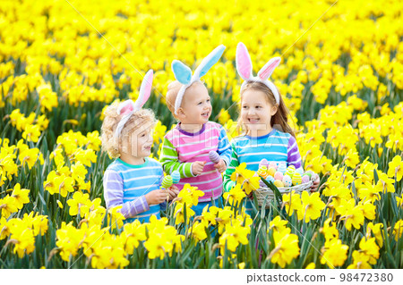 Kids with bunny ears on Easter egg hunt. 98472380