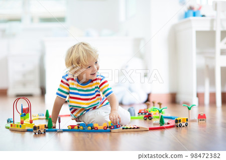Kids play wooden railway. Child with toy train. 98472382
