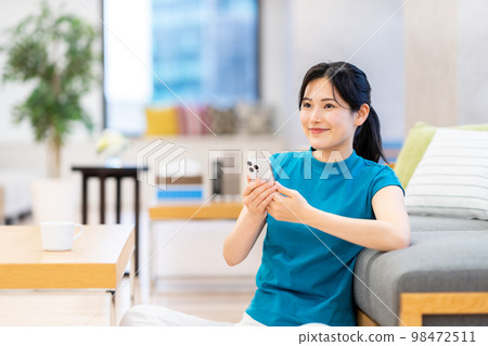 一名年輕女子在客廳裡使用智能手機。 98472511