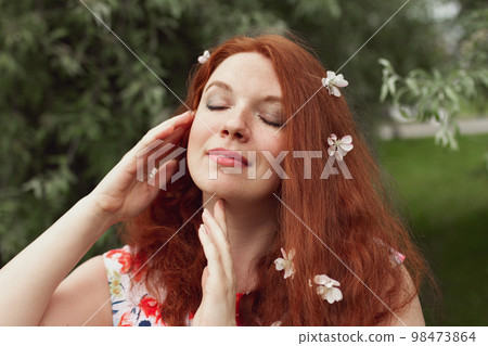 redhead young woman with closed eyes in white apple blossom, mental health concept redhead young woman with closed eyes in white apple blossom, mental health concept 98473864