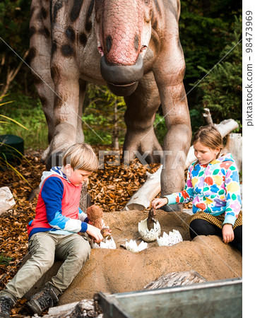 Little boy and girl playing with a dinosaur in dino park 98473969