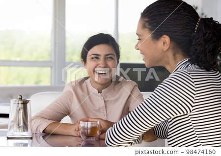 Cheerful excited diverse friend discussing good news in cafe Cheerful excited diverse friend discussing good news in cafe 98474160