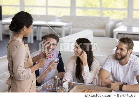 Indian waitress listening to group of happy customers in cafe 98474168