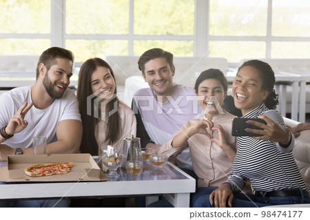 Happy multiethnic friends taking selfie on smartphone in cafe Happy multiethnic friends taking selfie on smartphone in cafe 98474177
