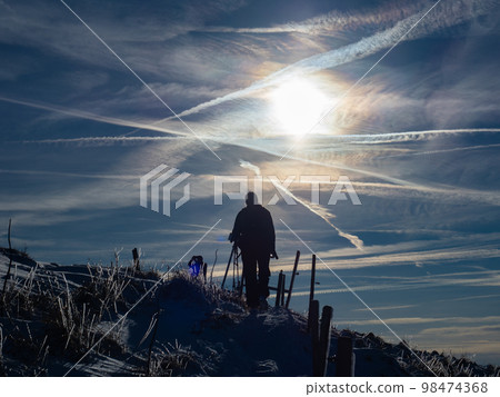 Lengries, Germany - December 28th 2022: A hiker on the last metres to the peak in the afternoon sunlight Lengries, Germany - December 28th 2022: A hiker on the last metres to the peak in the afternoon sunlight 98474368