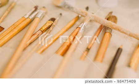 Art supplies. Painting tools. Artist kit. Paint instrument. Closeup of different used wooden professional paintbrushes set organizer. 98475409