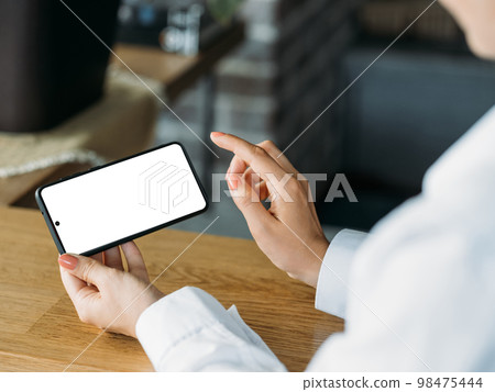 Digital mockup. Office woman. Mobile technology. Unrecognizable lady working smartphone with blank screen light office room interior. Digital mockup. Office woman. Mobile technology. Unrecognizable lady working smartphone with blank screen light office room interior. 98475444