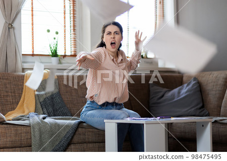 Young Caucasian woman screams and throws documents into camera. Business and mortgage concept Young Caucasian woman screams and throws documents into camera. Business and mortgage concept 98475495