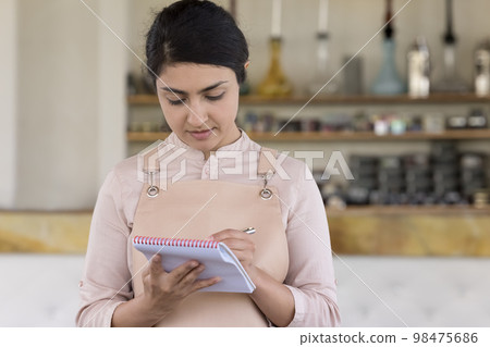 Young Indian female entrepreneur working in eastern cafe 98475686