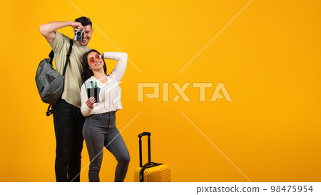 Cheerful millennial arabic guy takes photo camera and woman in glasses with suitcase and tickets rejoice to trip 98475954